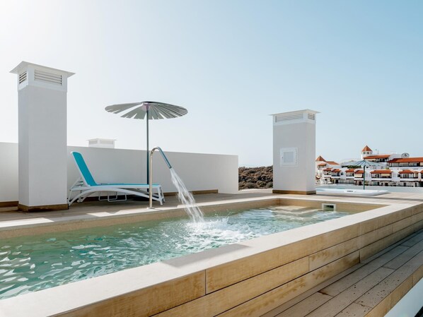 A rooftop pool with a water fountain, a lounge chair, and an umbrella. - Exclusive penthouse with sea view in La Caleta (La Caleta)