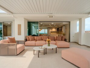 A modern living room with a sofa, two coffee tables, and a wicker chair. - Exclusive penthouse with sea view in La Caleta (La Caleta)