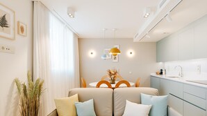 A modern living room with a sofa, a dining table, and a kitchen area. - Apartment 3 bedroom | ground floor| mountain view (La Caleta)