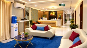 A hotel reception area with a reception desk, a sofa, and a water dispenser. - The Dritan Brookefield ITPL Main Road (Bengaluru)