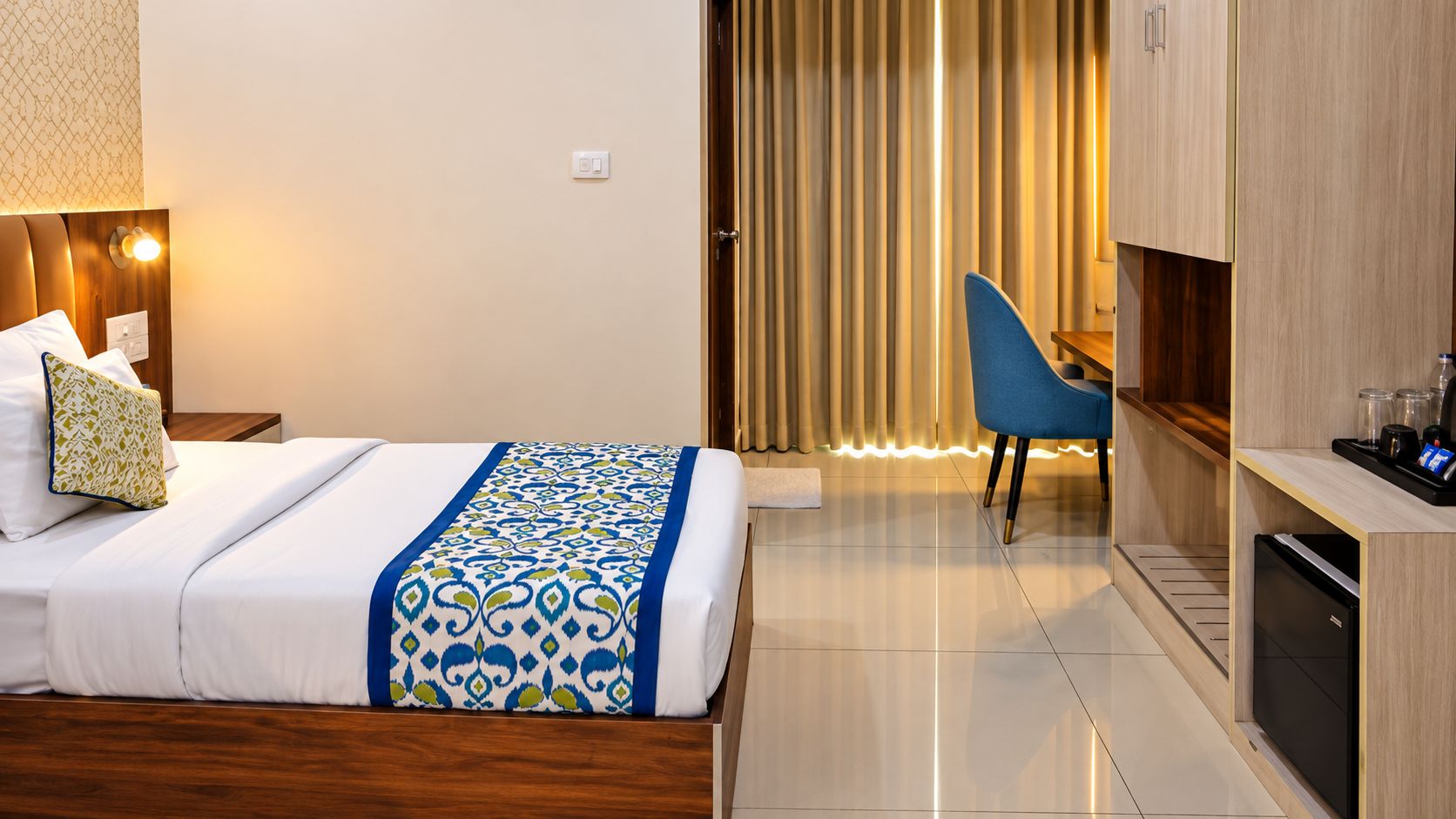 Una habitación de hotel con una cama, un escritorio, una silla y un mini bar.