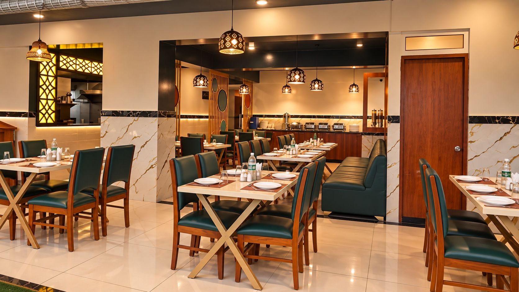 Un comedor de hotel con varias mesas y sillas, una cocina al fondo e iluminación colgante.