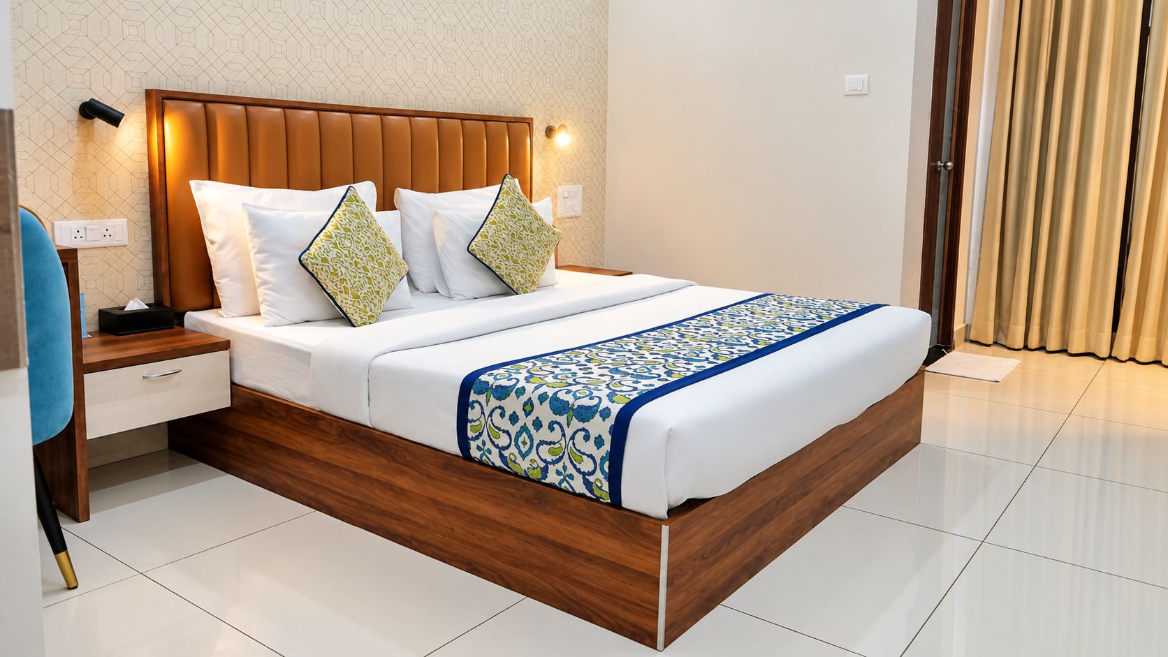 A modern hotel room with a wooden headboard, a white bedspread, and a patterned throw.