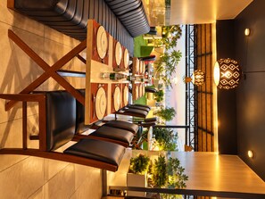 A modern dining area with a long table, multiple chairs, and a view of the outdoors. - The Dritan Brookefield ITPL Main Road (Bengaluru)