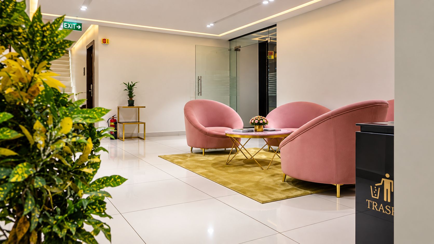 Decoração moderna com área de estar, incluindo cadeiras cor-de-rosa e uma mesa pequena, lixeira e extintor de incêndio.