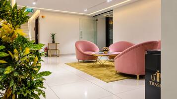 Decoração moderna com área de estar, incluindo cadeiras cor-de-rosa e uma mesa pequena, lixeira e extintor de incêndio.