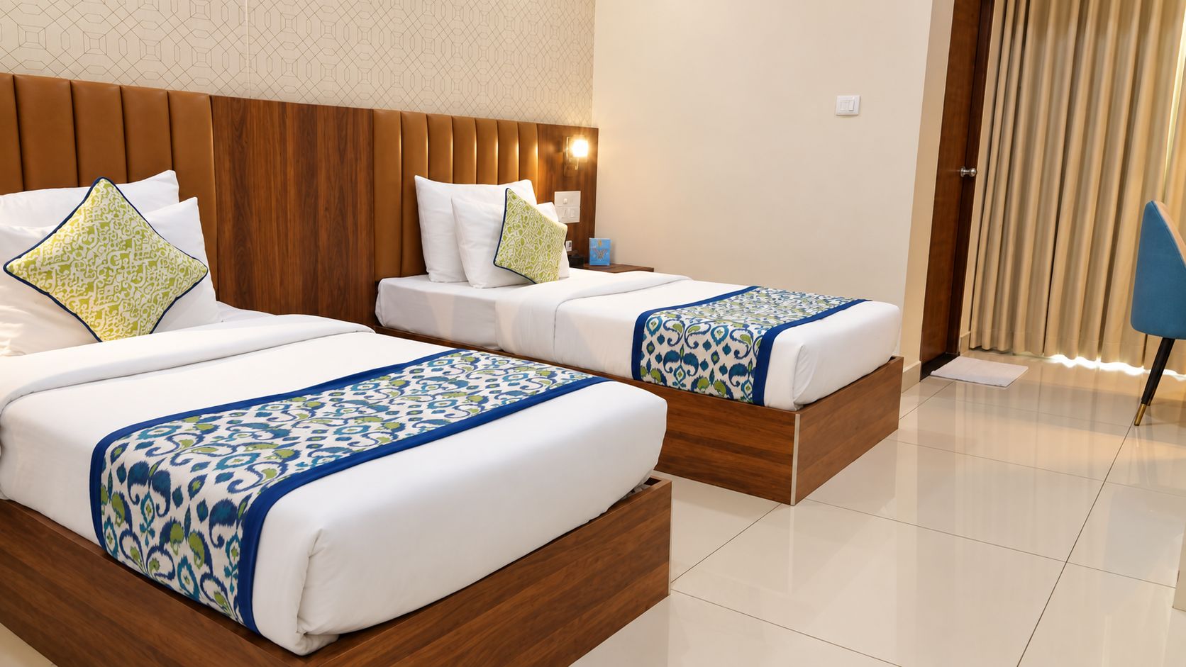 A hotel room with two beds, a wooden headboard, and a blue chair.
