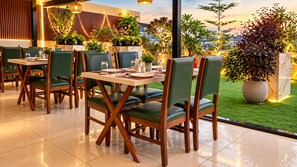 A restaurant with indoor seating, tables, chairs, and potted plants. - The Dritan Brookefield ITPL Main Road (Bengaluru)