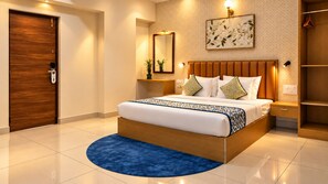 A modern bedroom with a wooden bed, a blue rug, a nightstand with a lamp, and a wardrobe. - The Dritan Brookefield ITPL Main Road (Bengaluru)