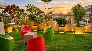 A rooftop terrace with artificial grass, potted plants, and modern seating. - The Dritan Brookefield ITPL Main Road (Bengaluru)
