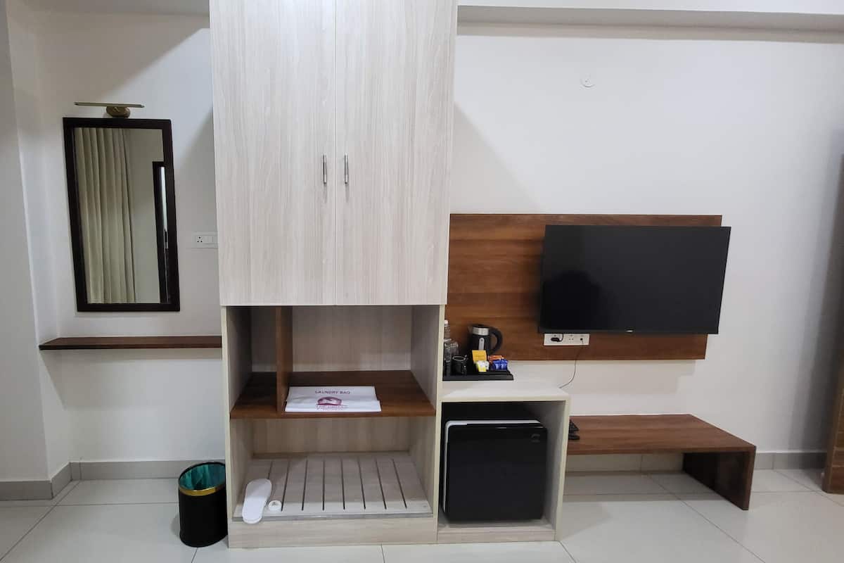 A modern living room with a built-in TV, a small shelf with a laundry bag, a trash bin, and a bench.
