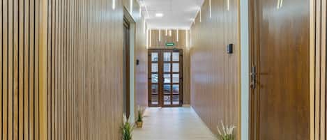 A hallway with wooden paneling, a door marked with the number 1, and potted plants.