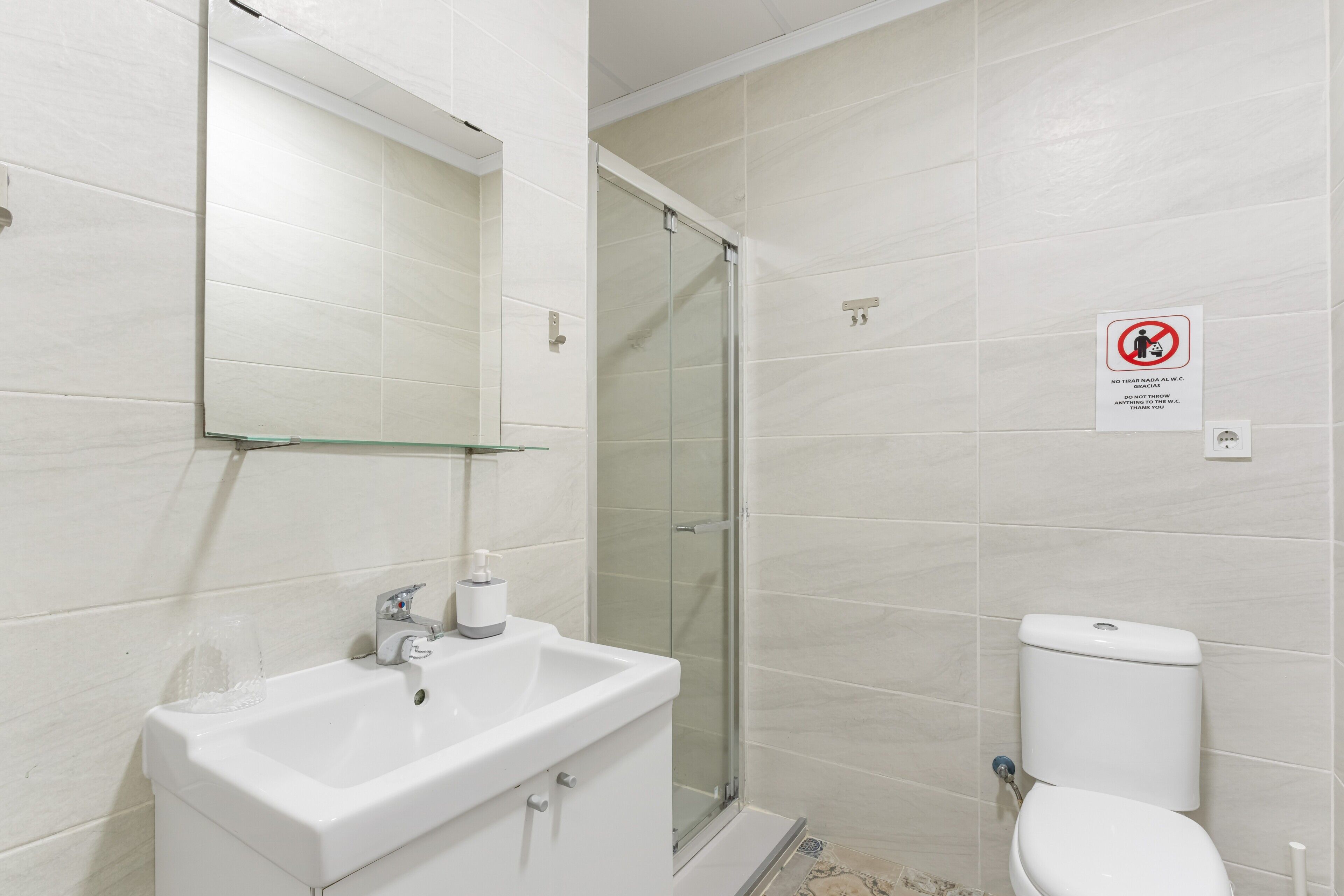 Une salle de bain équipée d’un lavabo, de toilettes et d’une douche à parois en verre.