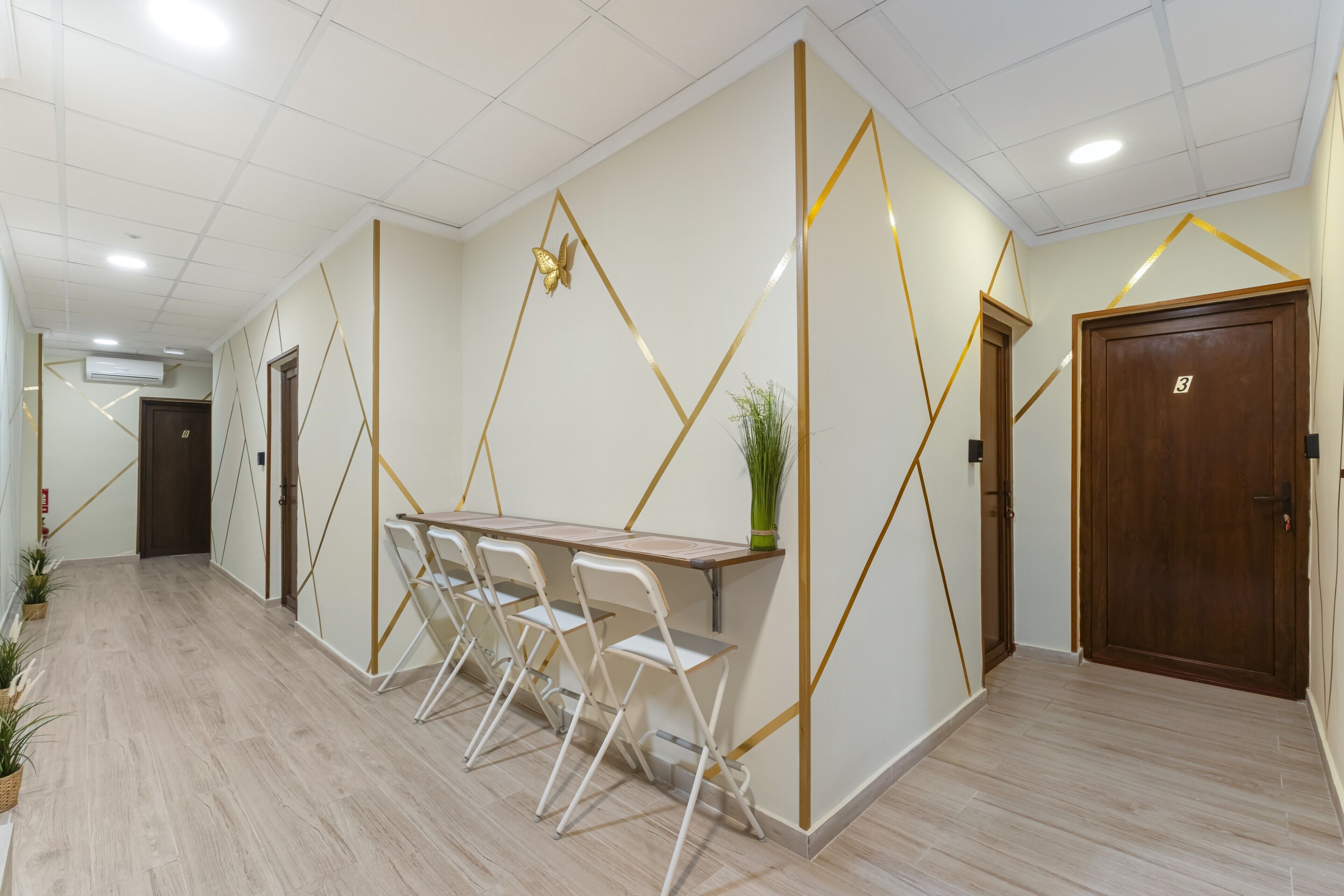A hallway with a wooden table and chairs, a potted plant, and a door marked with the number 3.