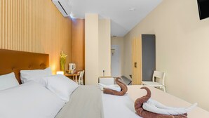 Une chambre d’hôtel avec deux lits, un bureau, une chaise et un téléviseur fixé au mur.