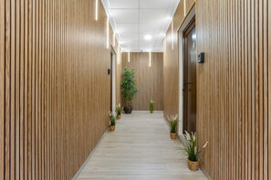 Un pasillo con paneles de madera, una planta en maceta y una puerta.