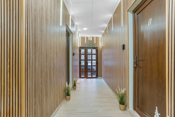 Un pasillo con paneles de madera, una puerta con el número 1 y plantas en macetas.