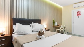 Une chambre d’hôtel comprenant un lit, une table de chevet, une lampe, une chaise, un bureau et une porte avec une pancarte.