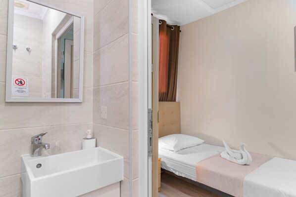 A hotel room with a bathroom, a bed, and a mirror.