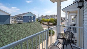 A balcony with a view of neighboring houses, a railing, and a chair. - Z Estates | Balcony Beach View Townhome + Pool (Ocean City)
