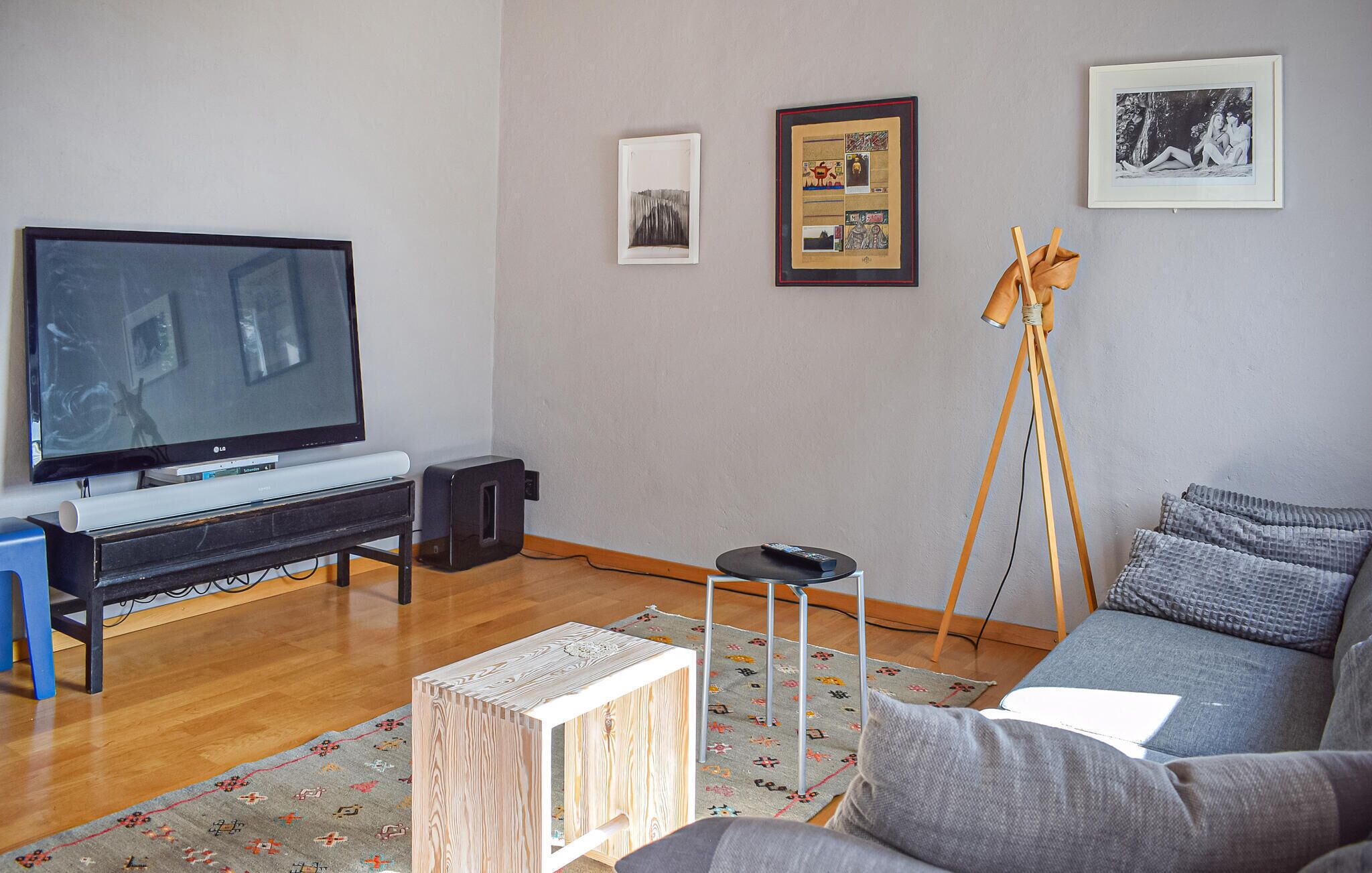 A living room with a flat-screen TV, a piano, a tripod, and a sofa.