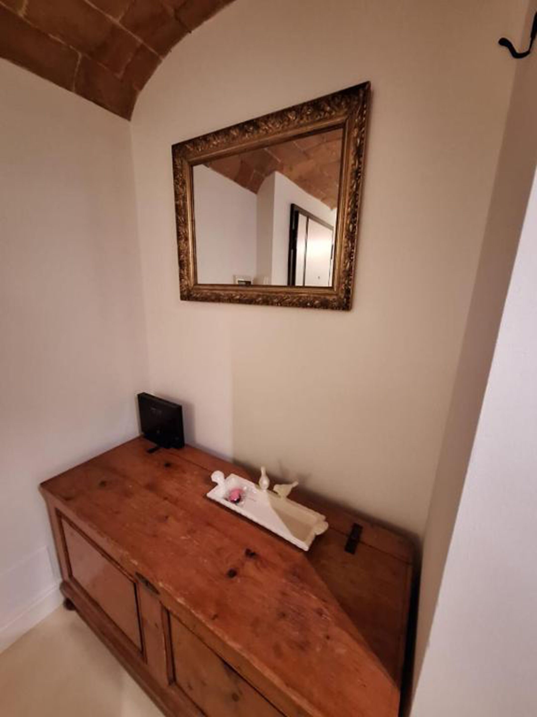 Een badkamer met een houten wastafelmeubel, een spiegel met een sierlijke lijst en een handdoekrek.