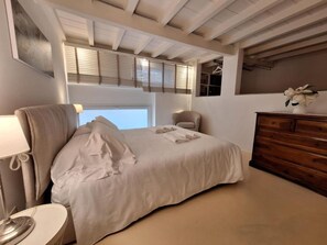 Un dormitorio con cama, cómoda, silla y ventana con persianas.