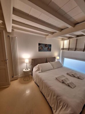 Una camera da letto con un letto grande, due lampade sui comodini, un termosifone e un quadro appeso al muro.