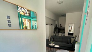 Ein modernes Wohnzimmer mit einem dunklen runden Tisch, einer Couch und einer Küche im Hintergrund.