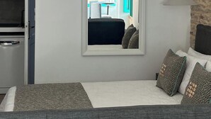 Ein Schlafzimmer mit Bett, Spiegel, Kleiderschrank und Blick auf einen Außenbereich mit Tisch und Stühlen.