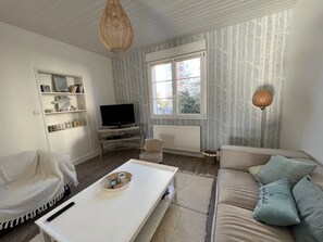 Una sala de estar con sofá, mesa de centro, televisor y estantería.