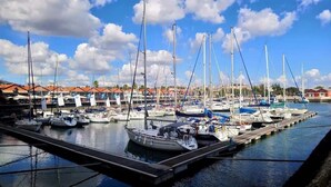 A marina with multiple boats docked at piers, surrounded by buildings with red roofs. - Sunset Terrace • Tagus Views • Walk to LX Factory (Lisbon)