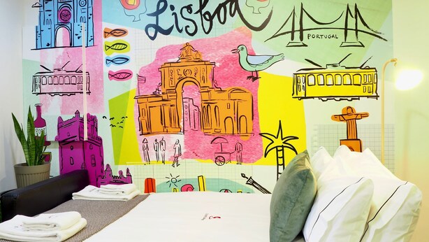Een hotelkamer met een kleurrijke muurschildering van bezienswaardigheden en de tekst 'Lisboa'.