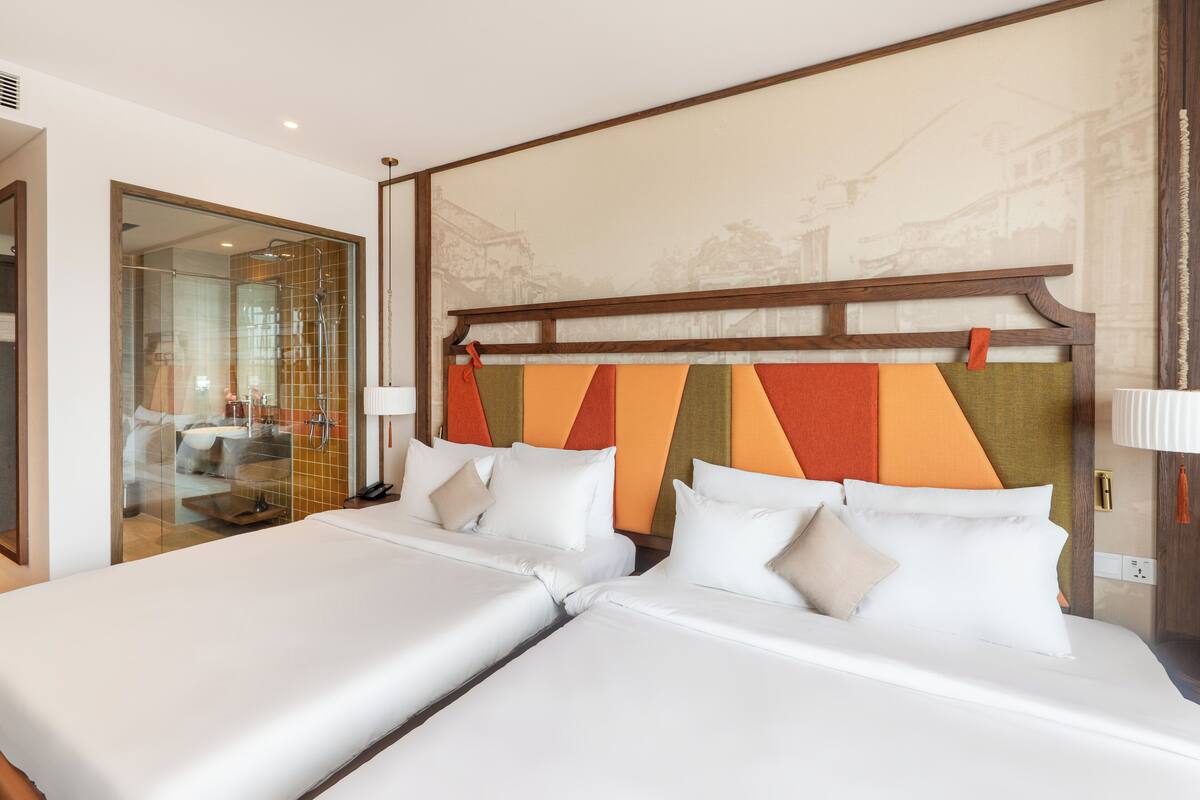 Une chambre d’hôtel avec deux lits, une douche en verre et une fresque murale.