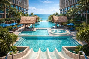 A hotel pool area with a central water slide, lounge chairs, and umbrellas. - Sky By Mandala Mũi Né (Mui Ne)