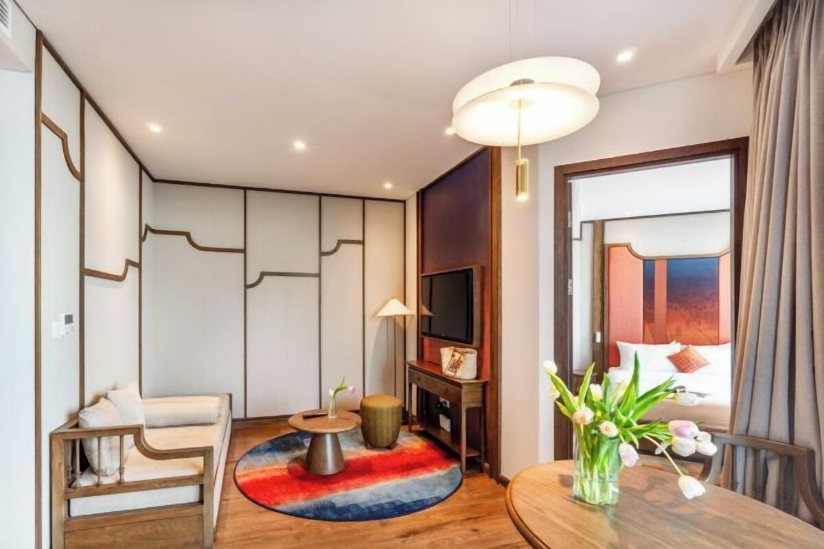 A modern living room with a sofa, a coffee table, a TV, and a red rug.