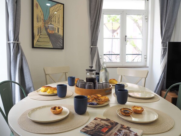Une table à manger avec des assiettes remplies de nourriture, des tasses bleues et une cafetière.