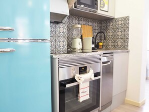 Une cuisine avec un réfrigérateur bleu, un four à micro-ondes, une machine à café et un grille-pain posés sur le plan de travail.