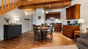 Un vaste espace de vie comprenant une table à manger, des chaises en bois, un buffet en bois foncé et une cuisine avec des meubles en bois et un four à micro-ondes.