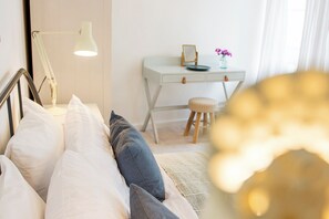 Een slaapkamer met een bed, een bureau, een kruk en een lamp.