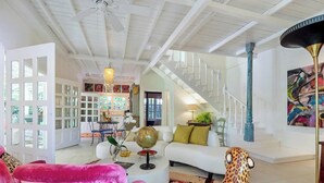 A spacious living area with a white sofa, a pink chair, a globe, and a leopard print rug. - Casa Agogó - Carribean house/pool/steps from beach (Puerto Viejo de Talamanca)
