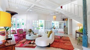 A spacious living area with a high ceiling, white walls, and a staircase leading to an upper level. - Casa Agogó - Carribean house/pool/steps from beach (Puerto Viejo de Talamanca)