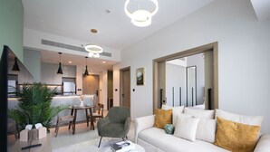 A modern living room with a white sofa, a green armchair, and a coffee table. There is a dining area with a table and chairs in the background. - KeyRock Golf Gate - Stylish Retreat (Dubai)
