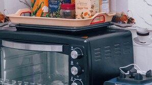 A kitchen with a toaster oven, a blender, and various food items on a tray. - Victorious Chillzone Hostel (Arusha)