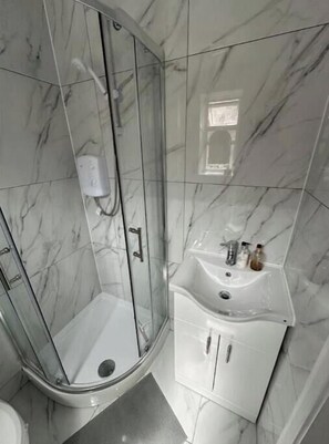 Een douche, handdoeken, zeep, toiletpapier