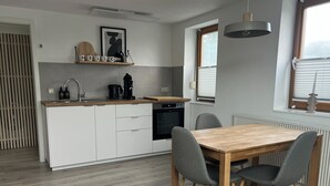 Una cocina moderna con armarios blancos, una mesa de comedor de madera y sillas grises.