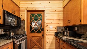 Una cocina con armarios de madera, una estufa de acero inoxidable, un microondas y una cafetera.