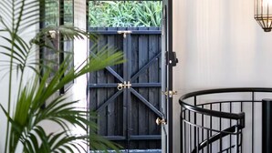 A modern interior with a staircase, a wooden door, and a view of greenery outside. - UNIQUE- Boutique Designer - The Barn Paddington (Sydney)
