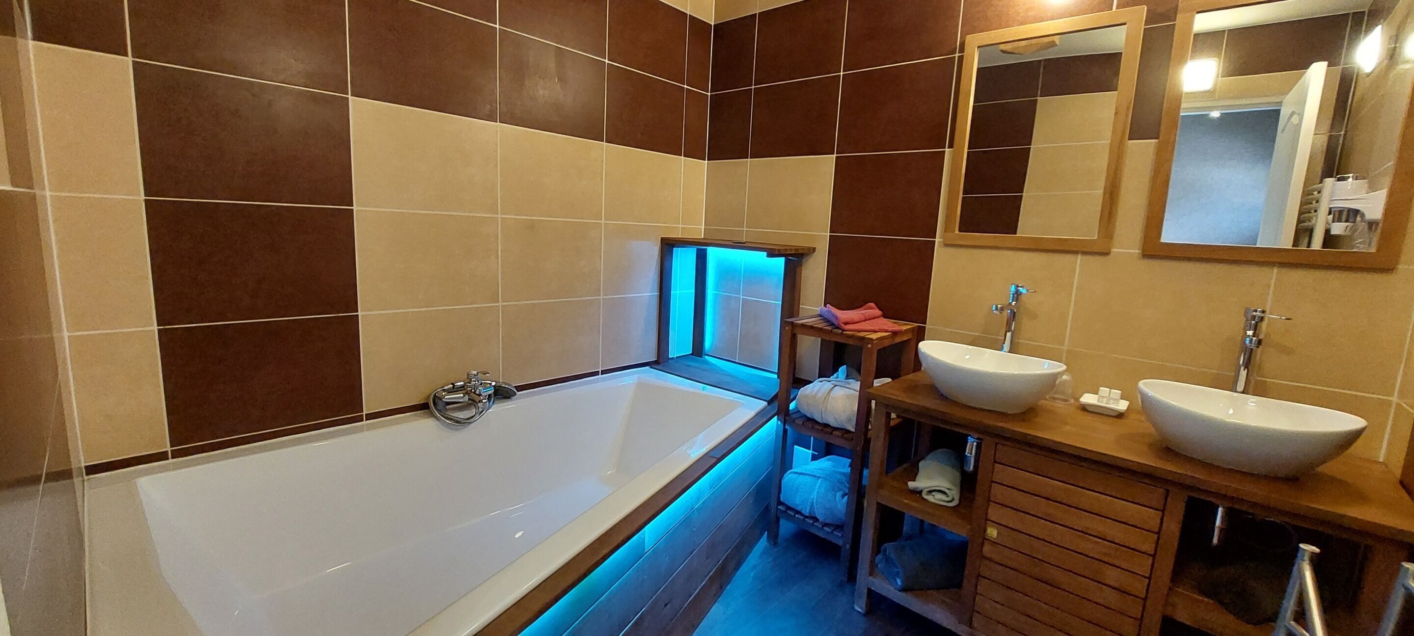 Un baño moderno con una bañera grande, dos lavamanos y un tocador con estantes.