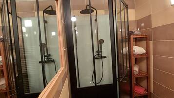 Un espacio de ducha con puertas de vidrio, repisas de madera con toallas y un revestimiento de azulejos.